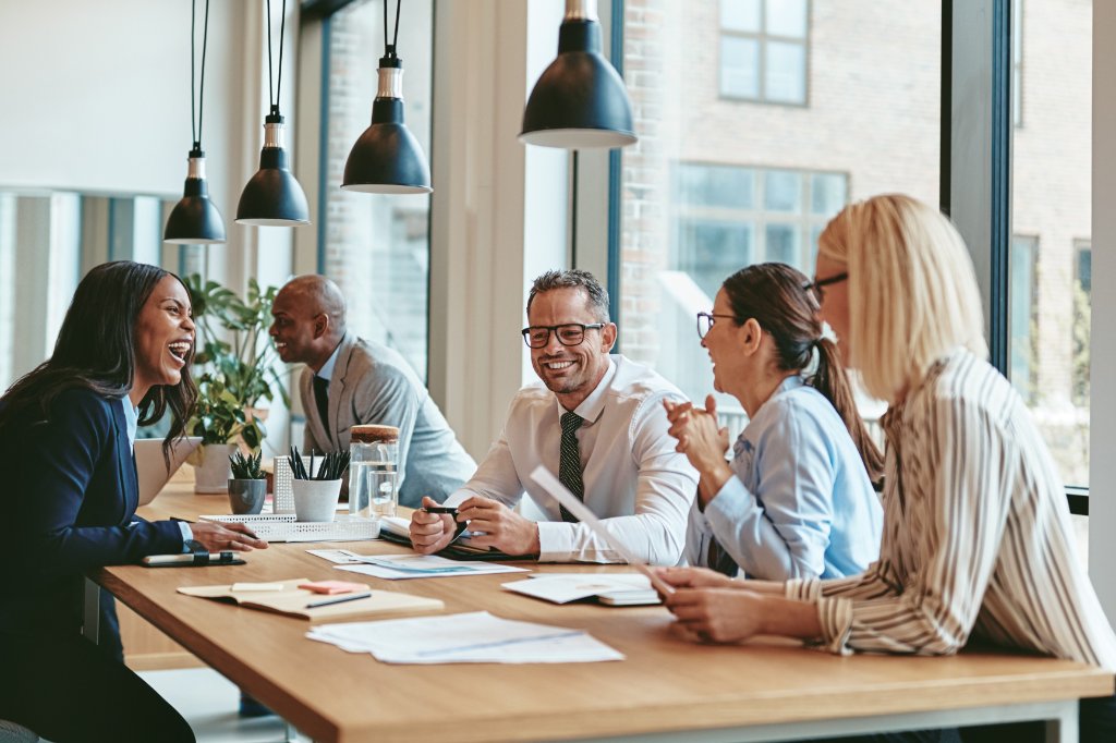Diverse business team laughing in a modern office meeting